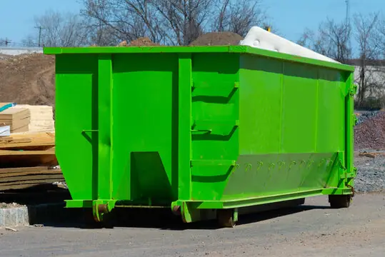 Green roll-off dumpster at a construction site